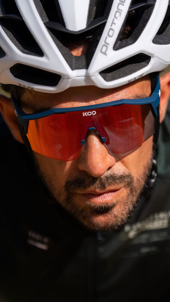 Koo Alibi met oranje lens, gedragen onder een witte racefietshelm