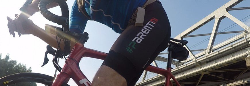 Parentini bibshort tijdens het rijden — logo op de broekspijp, close-up bij een brug
